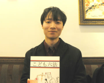 大学時代に研究奨励金で制作した「こども六法」を手にする山崎聡一郎さん