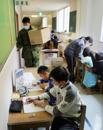 避難所となった学校の廊下で勉強する子どもたち（2011年4月、時事）