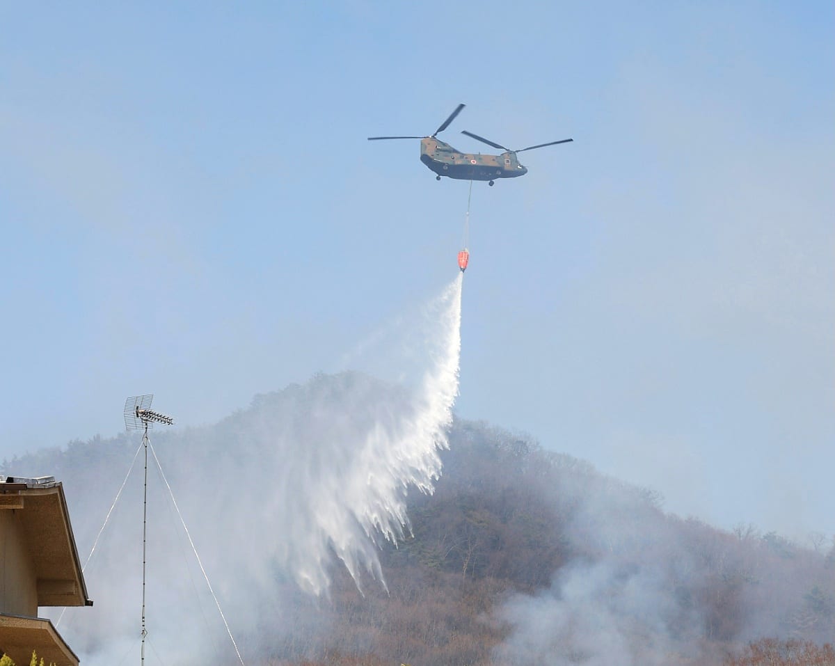 足利市の山火事で消火活動をする自衛隊ヘリ（2021年2月、時事）