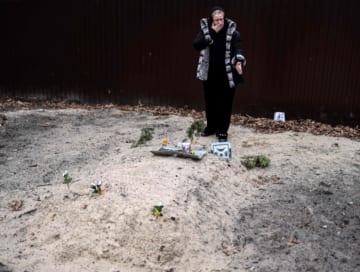 ウクライナのブチャで、息子を埋葬した墓の前で泣く母親（2022年4月、AFP＝時事）