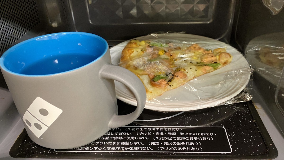 水を入れたコップと一緒に電子レンジでピザを温めると、生地がふわふわ、もちもちとした状態になる。加熱時間は、冷蔵保存していた場合は500ワットで1分弱、冷凍保存していた場合は500ワットで3分弱(ドミノ・ピザ ジャパン提供)